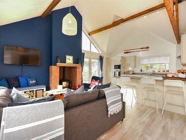 An open living room and kitchen area with a fireplace and blue accent wall at Bowline Cottage in Beadnell
