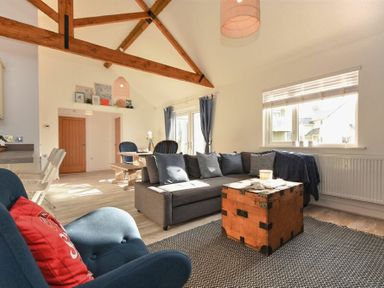 A living area with a gray sofa and wooden chest coffee table near a window at Bowline Cottage in Beadnell