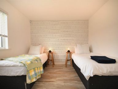 A bedroom with two single beds a wooden floor and a window at Bowline Cottage Beadnell