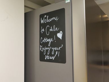 A welcome note on a chalkboard attached to a refrigerator at Coble Cottage in Craster