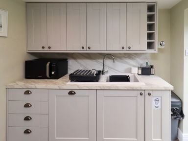 A kitchen with cabinets, sink, microwave, and dish rack at Coble Cottage, Craster