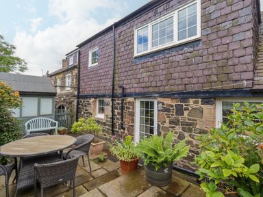 A garden with outdoor furniture and plants at Coble Cottage Craster
