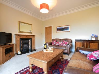 A living room with leather sofas wooden coffee table and fireplace at Sunnybrae Alnmouth