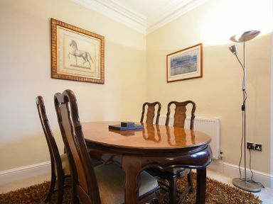 A dining room with wooden table and chairs two framed pictures on walls and a floor lamp at Sunnybrae Alnmouth