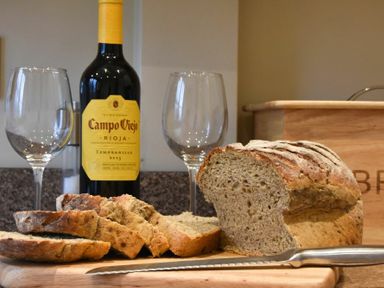 A sliced loaf of bread with a bread knife two empty wine glasses and a bottle of Campo Viejo Rioja wine on a kitchen counter at Sunnybrae Alnmouth