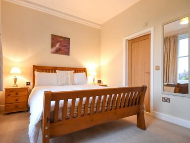 A bedroom with a wooden bed and bedside tables with lamps at Sunnybrae in Alnmouth