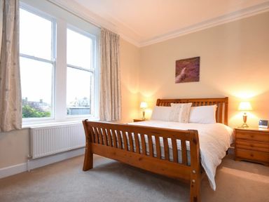 A bedroom with a wooden bed and two bedside tables with lamps at Sunnybrae in Alnmouth