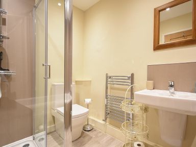 A bathroom with a shower cubicle toilet pedestal sink towel rack and a mirror at Sunnybrae (Alnmouth) in Alnmouth