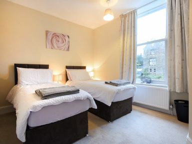 A bedroom with two single beds side by side with white bedding and folded towels on top at Sunnybrae in Alnmouth