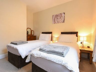 A bedroom with two single beds bedside tables and lamps at Sunnybrae Alnmouth