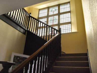A staircase with dark wooden railing and a large stained glass window at Sunnybrae Alnmouth