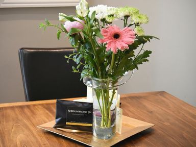 A vase with flowers and a packet of Northumberland Tea on a wooden table at Sandybrae in Alnmouth