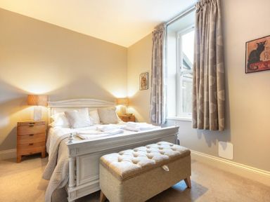 A bedroom with a double bed bedside tables lamps and a cushioned bench at Sandybrae in Alnmouth