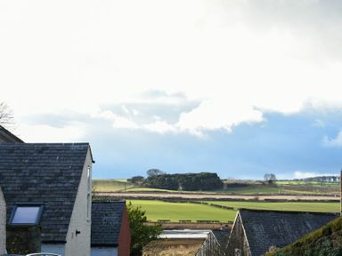 A view of rooftops with fields and trees in the background at Sandybrae in Alnmouth
