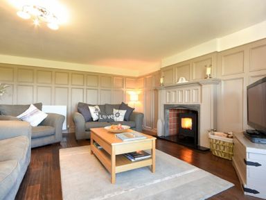 A living room with grey sofas wooden coffee table fireplace and television at Mariners House in Alnmouth