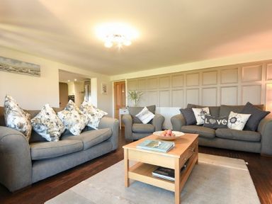 A living room with two sofas and an armchair around a wooden coffee table at Mariners House in Alnmouth