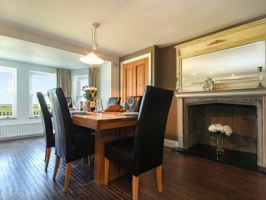 A dining room with black chairs around a wooden table near a fireplace at Mariners House in Alnmouth