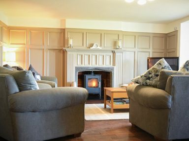 A living room with sofas a fireplace and a wooden coffee table at Mariners House in Alnmouth
