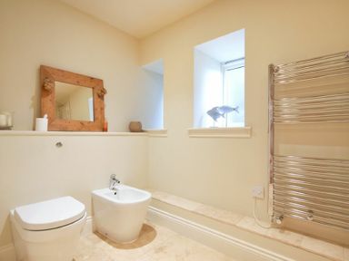 A bathroom with a toilet bidet mirror fish ornaments and a heated towel rail at Farne View Cottage in Seahouses