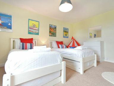 A bedroom with two white beds and colorful pillows and a dresser with a mirror at Farne View Cottage in Seahouses