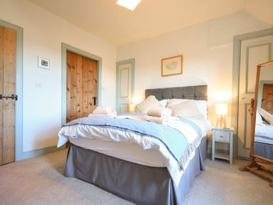 A bedroom with a bed towels bedside table lamp wooden doors and a mirror at Whistlewood in Bamburgh