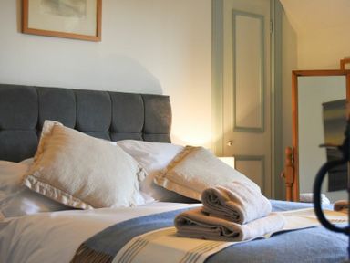 A bed with pillows and folded towels in a bedroom with a door and mirror at Whistlewood in Bamburgh