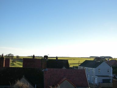 A view of rooftops with chimneys and fields in the background at Whistlewood in Bamburgh