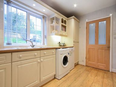 A kitchen with a washing machine under countertop beside a wooden door at Castle View Warkworth