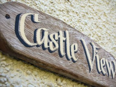A wooden sign with the text Castle View on a textured wall at Castle View Warkworth