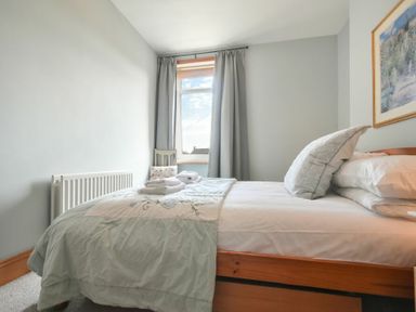A bedroom with a bed pillow towels window and curtains at Rosedale House in Amble