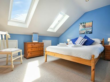 A bedroom with a wooden bed and dresser under skylights at Rosedale House in Amble