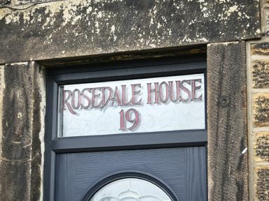 A door with stained glass above showing the text Rosedale House 19 at Rosedale House in Amble