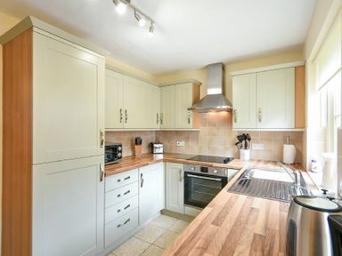 A kitchen with cabinets a stove oven a sink and countertop at Dryden Cottage in Bamburgh