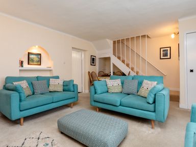A living room with two teal sofas and a patterned ottoman at Percy Cottages No4 in Alnmouth