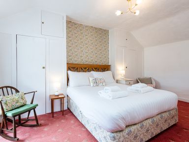 A bedroom with a double bed bedside tables lamps and a rocking chair at Percy Cottages No4 in Alnmouth