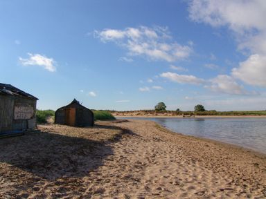 A beach scene with a shed and water at Percy Cottages No4 in Alnmouth