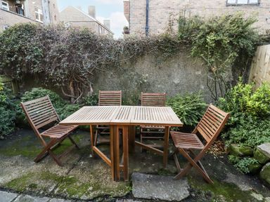 A garden with a wooden table and chairs at Percy Cottages No4 in Alnmouth