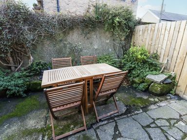 A garden with a wooden table and chairs at Percy Cottages No4 in Alnmouth