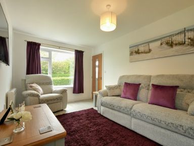 A living room with gray armchair sofa and purple cushions at The Chevy in Seahouses