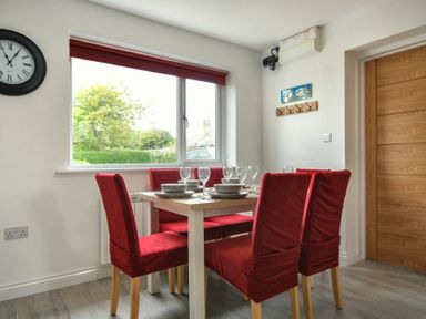 A dining room with a table set for four and red covered chairs at The Chevy in Seahouses