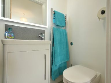 A bathroom with a white sink cabinet blue towels on a rack and a toilet at The Chevy in Seahouses