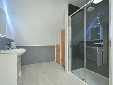A bathroom with a sink, wooden doors, and a shower enclosure at The Chevy in Seahouses