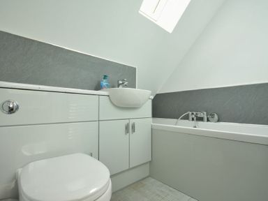 A bathroom with a toilet sink and bathtub under a sloped ceiling at The Chevy in Seahouses