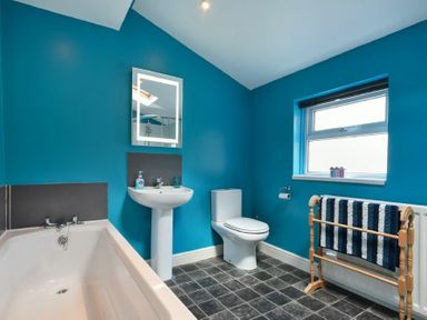A bathroom with a bathtub sink toilet window and a towel rail at Nettie's View in Amble