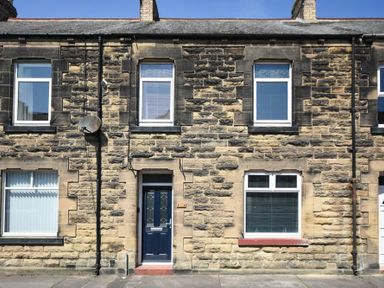 Stone terraced house with blue front door and four windows in Amble