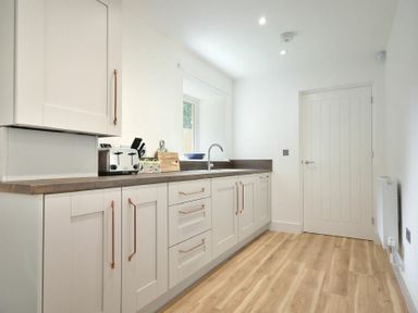 A kitchen with white cabinets wooden countertops a toaster and a knife block at The Lodge (Alnwick) in Alnwick