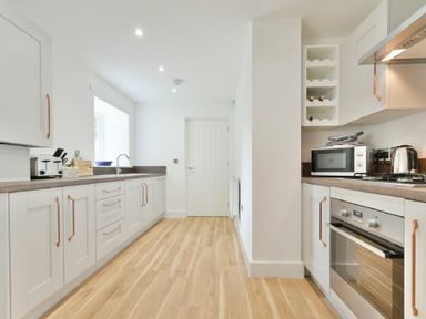 A kitchen with white cabinets wooden handles a toaster microwave kettle oven and a sink at The Lodge Alnwick