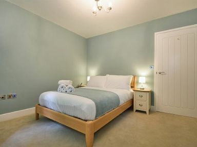 A bedroom with a double bed bedside tables lamps and a closed door at The Lodge (Alnwick) in Alnwick