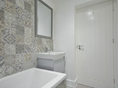 A bathroom with a bathtub sink mirror and a door at The Lodge Alnwick