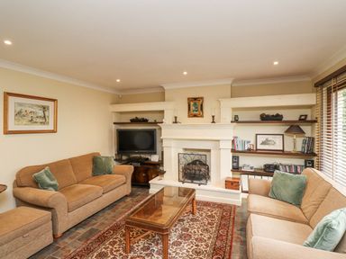 A living room with two sofas a coffee table a fireplace a television and shelves at Rokeby in Bamburgh